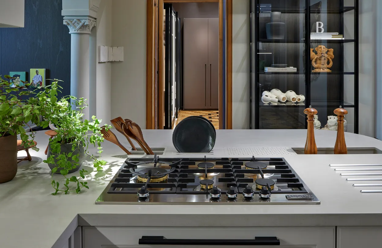 Cooktop a gás em ilha branca, com estante iluminada ao fundo